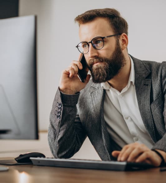 homem de negócios no celular na frente de um computador